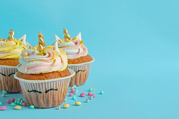 Cute sweet unicorn cupcakes on light blue background, space for text