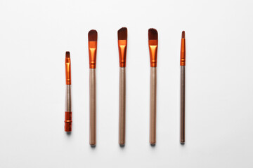 Different makeup brushes on white background, flat lay