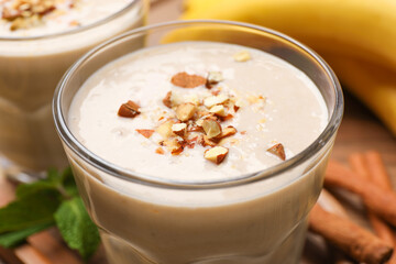 Tasty banana smoothie with almond and cinnamon on wooden table, closeup