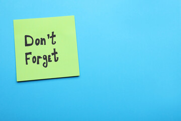 Paper note with phrase Don' t Forget on blue background, top view. Space for text