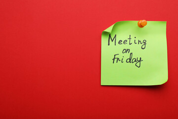 Paper note with words Meeting on Friday pinned to red background, space for text