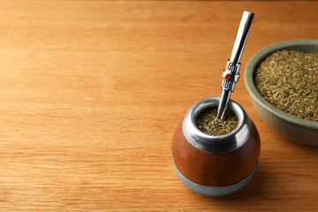Calabash with mate tea and bombilla on wooden table. Space for text