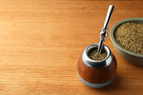 Calabash with mate tea and bombilla on wooden table. Space for text