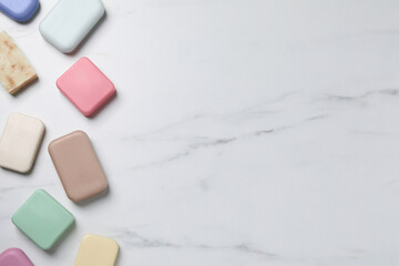 Many different soap bars on white marble table, flat lay. Space for text