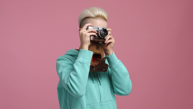 Cheerful, smiling woman taking pictures in the studio. Close-up view of professional female photographer working indoors. High quality 4k footage