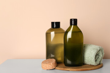 Solid shampoo bar and bottles of cosmetic product on white table, space for text