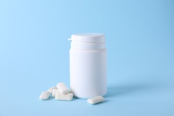Jar with tasty chewing gums on light blue background