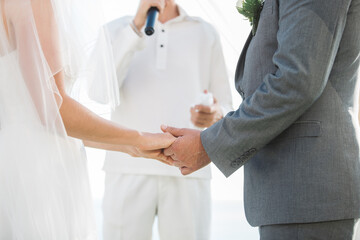 Obraz premium The groom and the bride attend the ceremony at the wedding. hand in hand with the pastor in the middle.