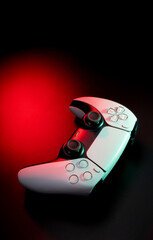 Modern white gamepad illuminated in red and blue. Game controller for video games and e-sports on a dark back. © solidmaks