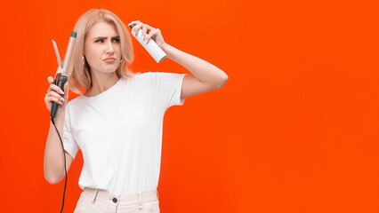 blonde woman on orange background with hair styler doing hair styling