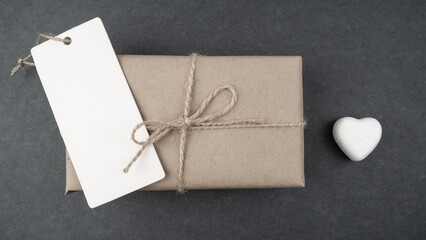 Gift box wrapped in kraft paper with white hearts on a gray background. Holiday concept. Valentine's Day. 