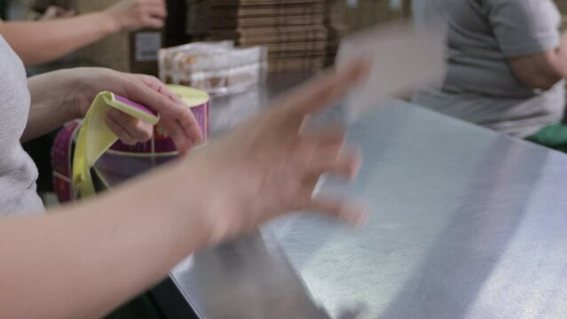 The workers of the tea factory manually glue labels to tea packages.