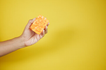 holding a Homemade natural soap bar against yellow background 