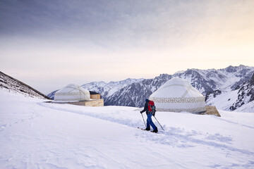 Man skiing near yurt house snowy mountains
