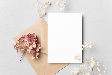 Blank wedding invitation card mockup with dried flowers on grey background. Flat lay, top view,...