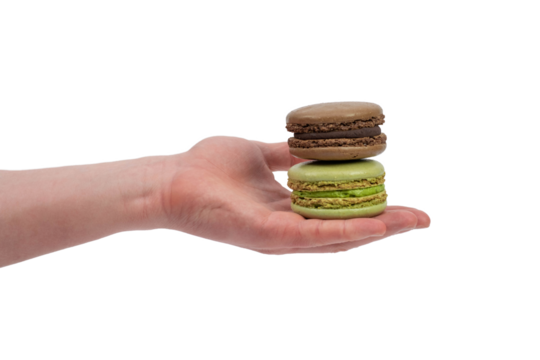 Male hand holding 2 sweet macaroons isolated on white. Green and chocolate macaroons. French dessert