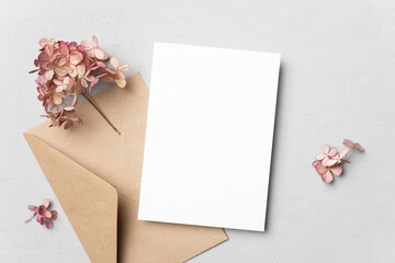 Blank wedding invitation or greeting card mockup with flowers and envelope