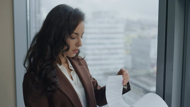 Woman ceo reading documents business contract standing at office window close up