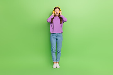 Fototapeta premium Full length photo of cute nice positive impressed girl wear denim jeans purple pullover headphones dancing isolated on green color background