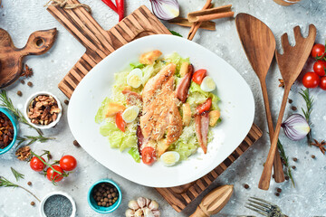Caesar salad with chicken fillet and cherry tomatoes. On a white plate. On a gray stone background. Restaurant menu.