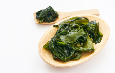 Laminaria Kelp Seaweed in a wood bowl on White table Background © boommaval