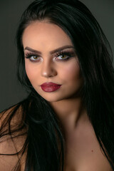 Female model with dark straight long hair and evening makeup.