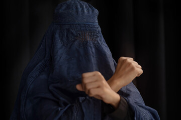Muslim woman in Burka or Burqa, tradition cloths in Afghanistan and West Pakistan showing fist gesture for against violence and human rights on black background