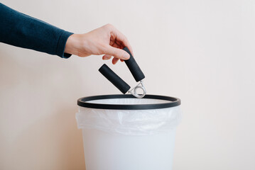Close-up of person throwing an expander hand trainer into wastebasket