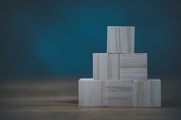 Business development concept by wood block construction. Growth idea and strategy. Stack of square wooden cubic toy. Background for success, leadership, challenge, creativity and performance in career