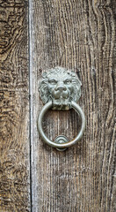 Metal lion head door knocker on an old wooden door