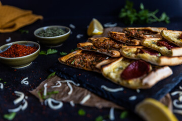 Turkish pide pastry baked in a stone oven served on stone plate with minced meat and cheese