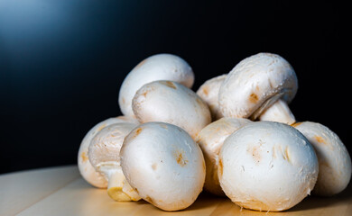 champignon mushrooms on a wooden table on a black background