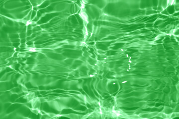 Defocus blurred transparent green colored clear calm water surface texture with splashes and...