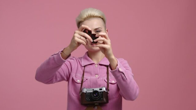 Charming, female photographer holding professional camera indoors. Smiling woman amazed while looking at photos. High quality 4k footage