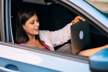 Young woman using laptop in her car