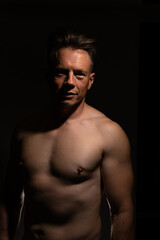 Sexy portrait of muscular handsome topless male isolated against a black background
