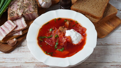 Traditional Ukrainian borscht . White plate of red beet root soup borsch with white cream, green onion, sliced salted pork lard (salo). Beet Root delicious soup. Traditional Ukraine food cuisine