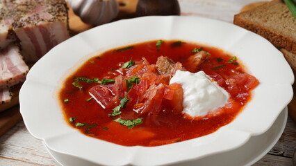 Traditional Ukrainian borscht . White plate of red beet root soup borsch with white cream, green onion, sliced salted pork lard (salo). Beet Root delicious soup. Traditional Ukraine food cuisine