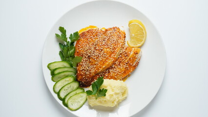 Fresh backed red tilapia fillet on white plate with lemon and herbs
