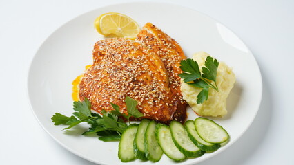 Fresh backed red tilapia fillet on white plate with lemon and herbs