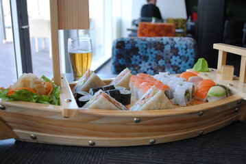 Sushi and rolls set in Boat bar from reclaimed wood  with a glass of beer in a seafood restaurant