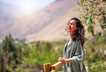 mid adult latin woman with eyes closed and head raised enjoying the sun and the breeze in Paihuano,...