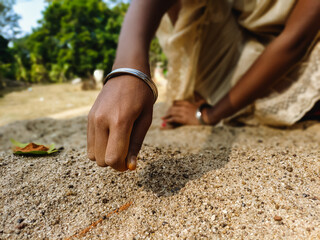 Little girl making designs on sand with red colors
