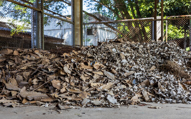 A large amount of dead leaves are piled together in the old steel grate structure room.