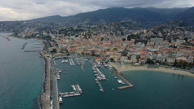Aerial view of Sanremo, Italian city on the seashore in Liguria, north Italy. Drone flying along the port over beaches and boardwalk with palm trees and Birds Eye of yacht parking in San Remo, Italy.