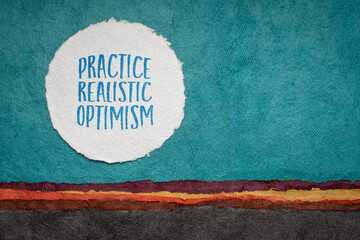 practice realistic optimism - inspirational advice or reminder, writing against abstract paper landscape, positivity concept - obrazy, fototapety, plakaty