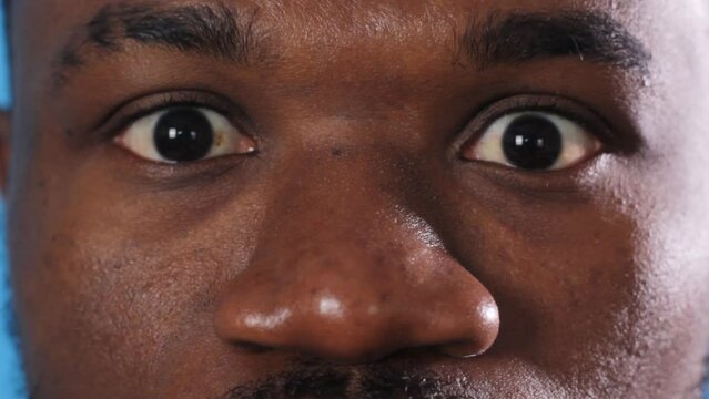 a large portrait of the face of an African American man abruptly opening his eyes looking into the camera