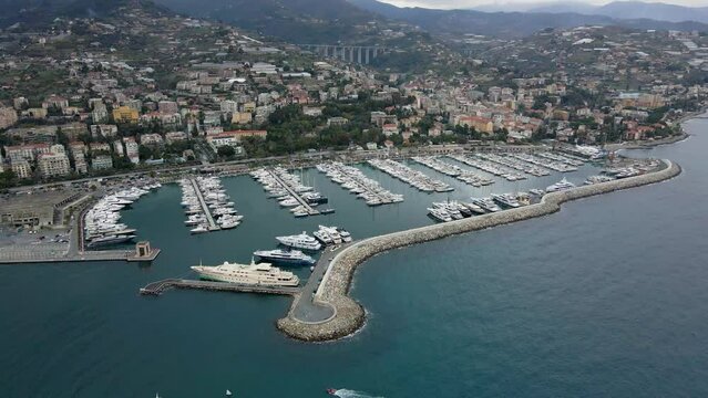 Aerial view of Sanremo, Italian city on the seashore in Liguria, north Italy. Drone flying along the port over beaches and boardwalk with palm trees and Birds Eye of yacht parking in San Remo, Italy.