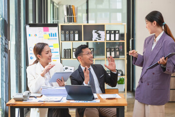 Asian business team consists of marketing staff. accountant and financial officer Help each other analyze company profits using tablets. calculator Laptop computers, graph paper, and corporate pens.