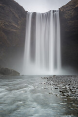 skógafoss, la cascata in lunga esposizione a formare una tenda d'acqua con visibile il fiume e i...